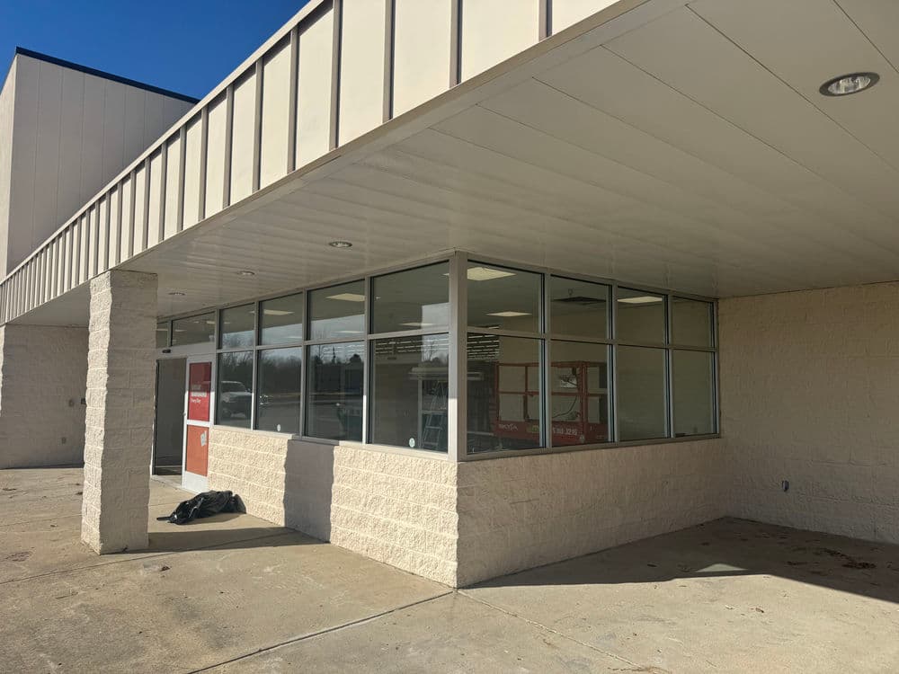 Exterior view of a commercial building featuring large glass windows and a beige façade.